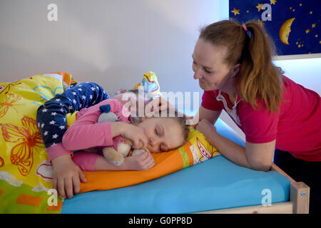 Sisters Skady-Lee (10) and Lucy-Mae (6) lie on a bed next to their mother Wiebke Ruedig at the night nursery at the Kapernaum daycare center in Flensburg, Germany, 03 May 2016. The first night nursery in Schleswig-Holstein has opened in Flensburg. Requirements for the parents at the service nursery at the Diako Hospital are strict: children may not stay for 24 hours at a time or be brought in the middle of the night. Photo: CARSTEN REHDER/dpa Stock Photo