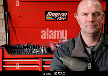 male motor mechanic standing in front of red tool box Stock Photo