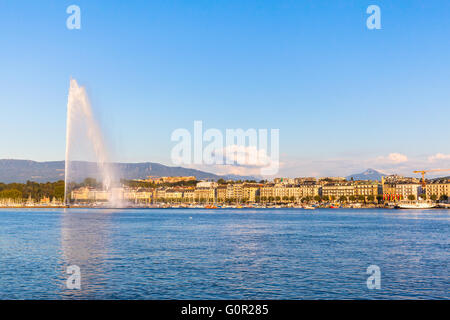 Beautiful view of the water jet fountain in the lake of Geneva and the cityscape of Geneva at sunset, Switzerland Stock Photo