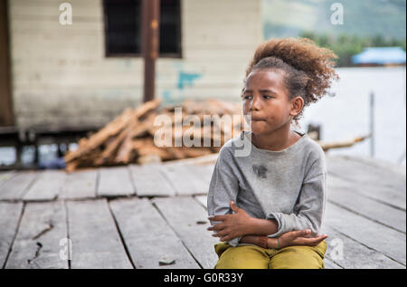 JAYAPURA, WEST PAPUA, INDONESIA - CIRCA FEBRUARY 2016: Papuan girl sitting with a dreamy face Stock Photo