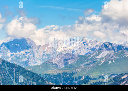 Panorama view on the hiking path on Bernese Oberland with trees in foreground and mountain range of the alps in background, Swit Stock Photo