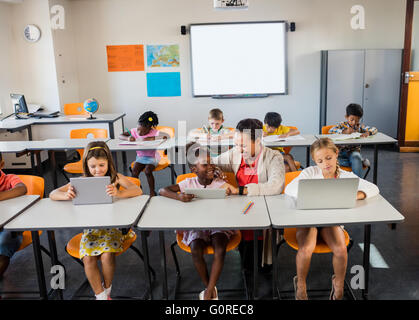 Children using technology with their teacher Stock Photo