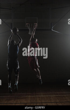 Basketball player shooting a basketball with a defender Stock Photo
