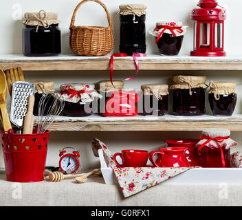 A rustic style. Ceramic tableware and kitchenware in red on the shelves. Stock Photo