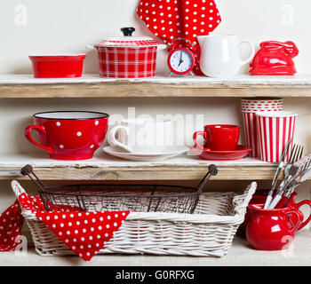 A rustic style. Ceramic tableware and kitchenware in red on the shelves. Stock Photo