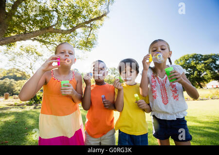 Children playing with bubble wand in the park Stock Photo