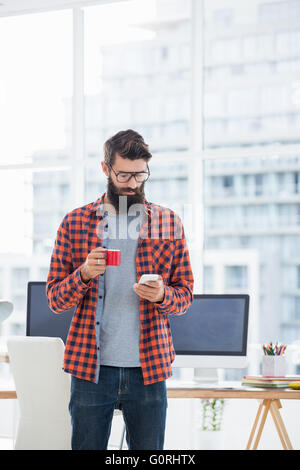 Hipster using smartphone and drinking coffee Stock Photo