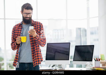 Hipster using smartphone and drinking coffee Stock Photo