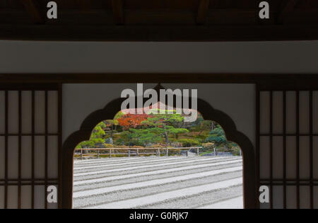 A view through a cusped alcove window shows the courtyard garden of carefully raked and sculpted silvery-white sand inside Ginkaku-ji, a Zen Buddhist temple and World Heritage Site in the northeast area of Kyoto, Japan. Stock Photo