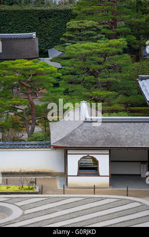 A hilltop telephoto view looks down onto cypress bark and kawara ceramic tile roofs, and the courtyard Zen garden of carefully raked and sculpted silvery-white sand inside Ginkaku-ji, a Zen Buddhist temple and World Heritage Site in the northeast area of Stock Photo
