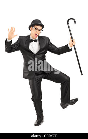 Full length portrait of a young male comedian dancing with a cane isolated on white background Stock Photo