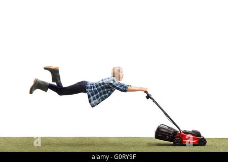 Woman mowing a lawn and being pulled by the lawnmower isolated on white background Stock Photo