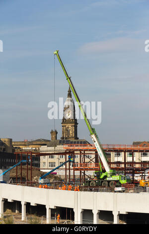 Construction work in progress on the new Bolton bus interchange with a mobile crane lifting sections of steelwork into place.