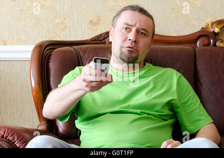 man with a TV remote control on sofa in the room Stock Photo