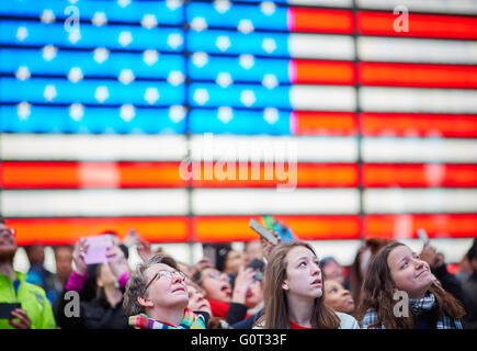 New York times Square   large neon lightbox flag tourists looking up a screens taking pictures mobile Stock Photo