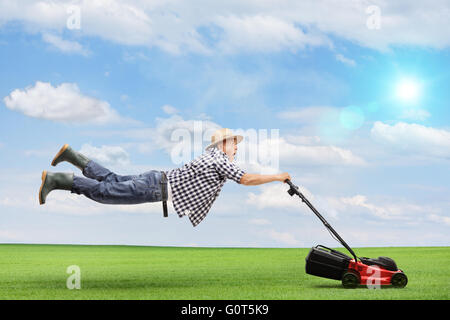 Mature man being pulled by a powerful lawnmower outdoors on a beautiful sunny day Stock Photo