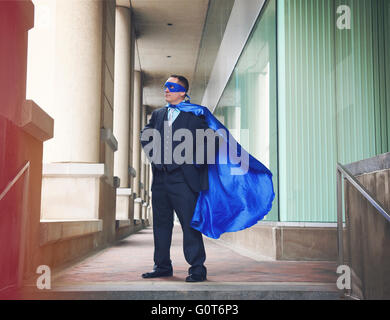A super business man is wearing a blue cape confident in the city for a success, entrepreneur or inspiration concept. Stock Photo