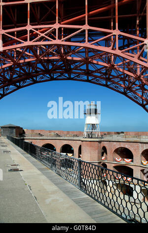 Golden Gate Bridge span arcing over lighthouse, Fort Point National Historic Site, San Francisco, California USA Stock Photo