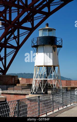 Golden Gate Bridge span arcing over lighthouse, Fort Point National Historic Site, San Francisco, California USA Stock Photo