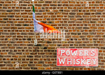 An Irish Tricolour and a sign for Power's Whiskey on a wall of an Irish pub in Dublin. Stock Photo