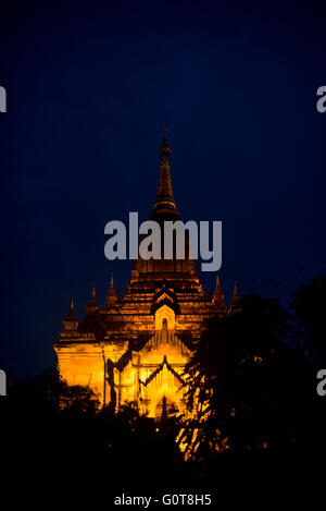 BAGAN, Myanmar — The Dhammayazika Pagoda stands silhouetted against the darkening sky at dusk in Bagan. Built in 1196 by King Narapatisithu, this circular-based pagoda with its distinctive pentagonal design and golden spire creates a striking outline as daylight fades. The structure's unique form contrasts with the typical square-based temples scattered across Bagan's ancient landscape. Stock Photo