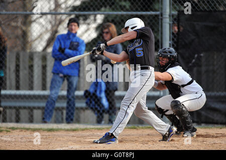 A hitter follows through on his swing following making contact with a pitch during a high school baseball game. USA. Stock Photo