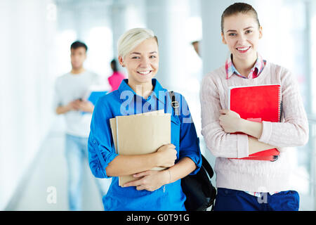 Two pretty students with books looking at camera Stock Photo