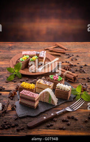 Assorted different mini cakes on vintage wooden table Stock Photo