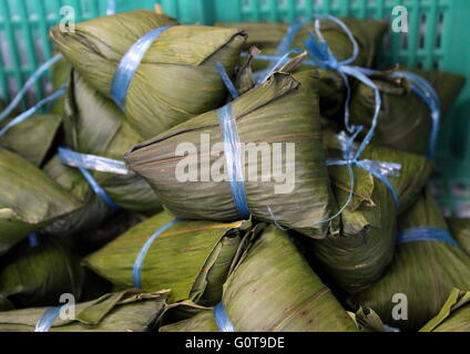 Chinese sticky rice dumplings, or zong zi, wrapped in bamboo leaves using eaten during Duanwu or Chinese Dumpling Festival celebration. Stock Photo