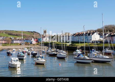 View along Afon Aeron River estuary to church with boats moored in harbour on incoming tide in coastal town. Aberaeron Wales UK Stock Photo