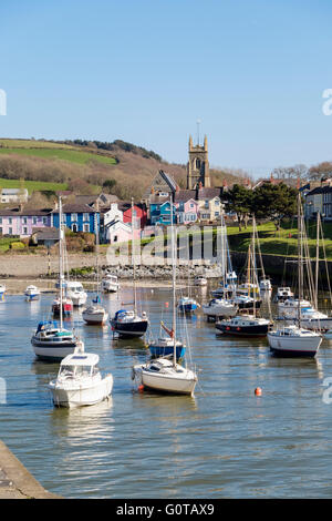 Looking along Afon Aeron River estuary to church with boats moored in harbour at high tide in coastal town. Aberaeron Wales UK Stock Photo