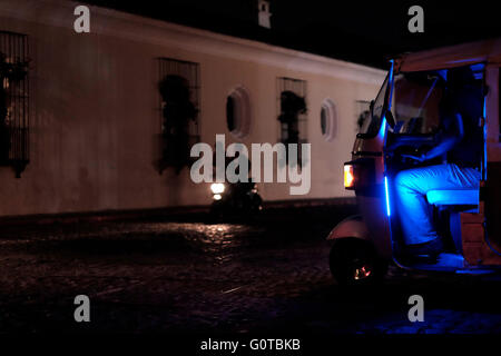 Motorcyclists driving through a dark street at night in Antigua a city in the central highlands of Guatemala famous for its well-preserved Spanish Baroque-influenced architecture and a UNESCO World Heritage Site. Stock Photo