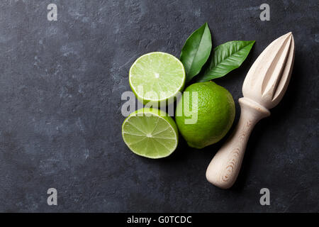 Limes and juicer on stone background. Top view with copy space Stock Photo