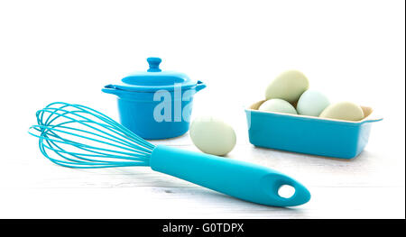 Eggs in a blue bowl with a whisk on a rustic white wood table top shot from above Stock Photo