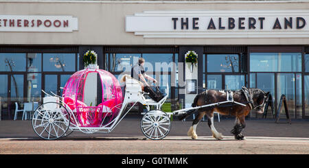 A pink princess-style fairy tale coach or novelty landau, non-traditional carriages plying for trade on Blackpool Promenade, Lancashire, UK Stock Photo