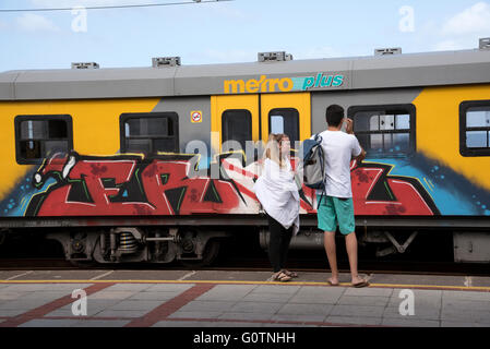 Young couple waiting for a railway train at Kalk Bay Station Western Cape South Africa Stock Photo