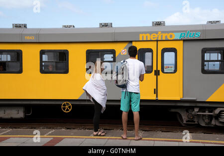 Young couple waiting for a railway train at Kalk Bay Station Western Cape South Africa Stock Photo