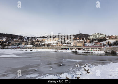 View of the icy Sankt Moritz lake and the city on the mountain in Winter, Grisons, Switzerland Stock Photo