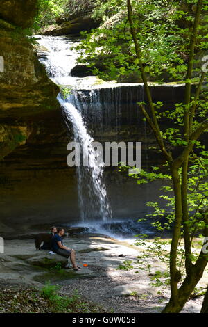 Hikers with a dog resting at the waterfall in La Salle Canyon at Starved Rock State Park on the banks of the Illinois River. Stock Photo