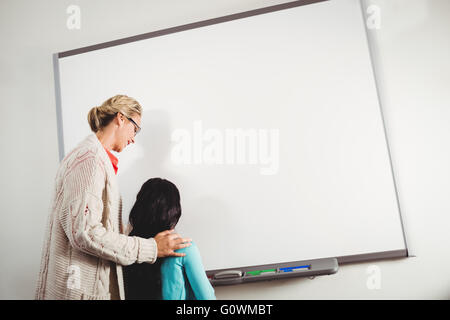 Teacher and pupil writing on whiteboard Stock Photo