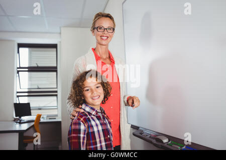 Teacher and pupil standing in front of whiteboard Stock Photo