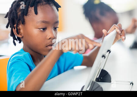 Close up view of pupil using tablet pc at desk Stock Photo