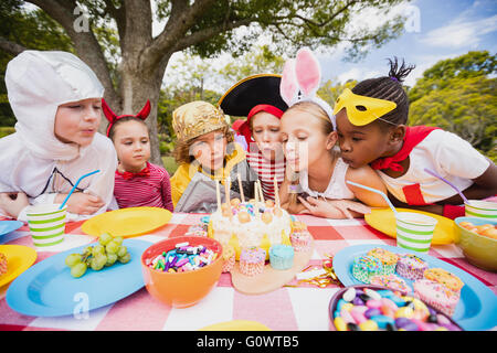 Cute children blowing together on the candle during a birthday party Stock Photo
