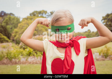 Little girl wearing superhero costume contracting biceps Stock Photo