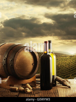 Wine bottles and wodden barrel, vineyard on background Stock Photo