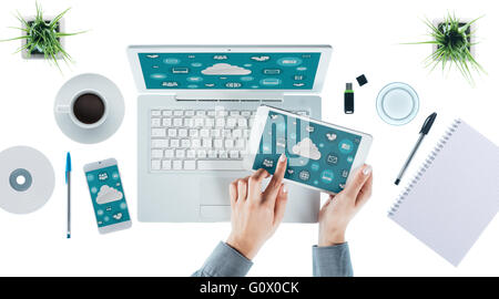 Cloud computing and multiplatform concept, user interface on laptop, tablet and smartphone, female hands touching an icon Stock Photo