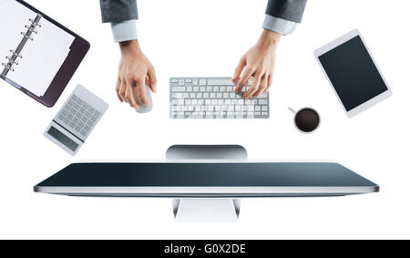 Executive businessman working on his computer at office desk, white background, hands top view Stock Photo