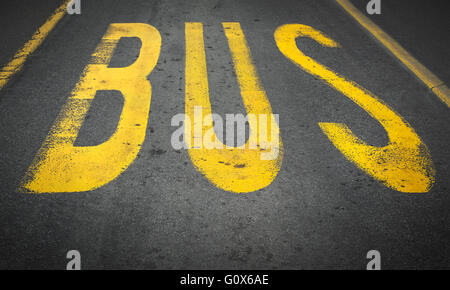 Yellow bus traffic sign painted on asphalt road. Stock Photo