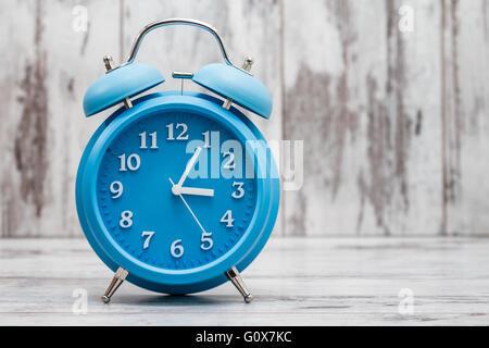 Blue retro alarm clock on white wooden background Stock Photo