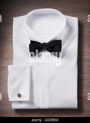 White, tuxedo shirt with a bow tie and cuff link, studio shot on wooden background Stock Photo